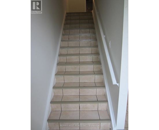 A staircase with beige tiles and white railings.