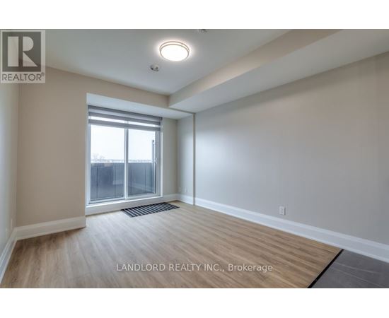 A spacious room with a large window and wooden flooring.