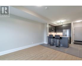 A modern kitchen with a bar stool and a fridge.