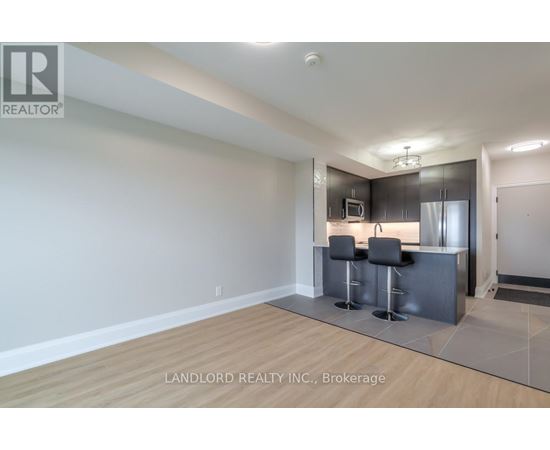 A modern kitchen with a bar stool and a fridge.