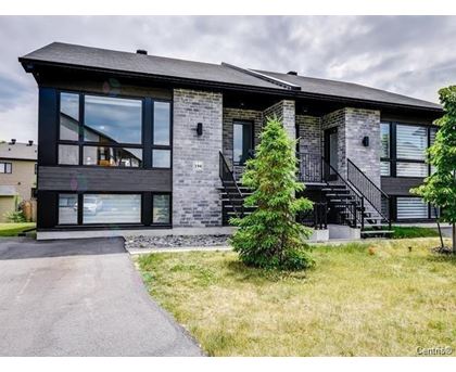 A modern house with a black roof and a stone facade.