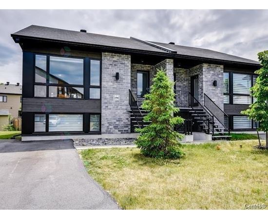 A modern house with a black roof and a stone facade.