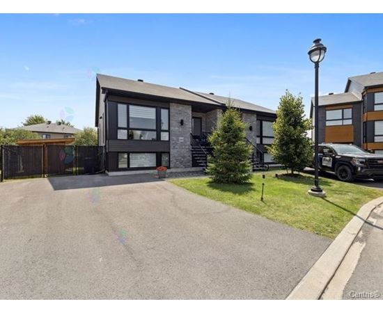 A modern house with a grey driveway and a black car parked in front.