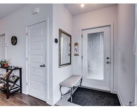 A hallway with a bench, a mirror, and a door.