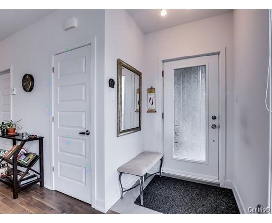 A hallway with a bench, a mirror, and a door.