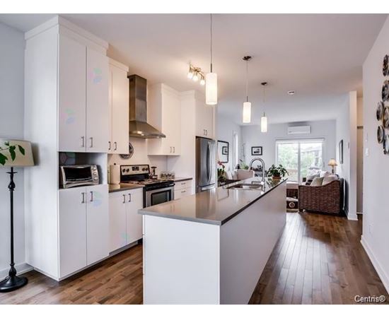 A kitchen with white cabinets and a wooden floor.