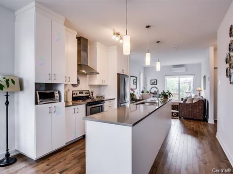 A kitchen with white cabinets and a wooden floor.