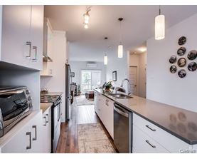 A kitchen with white cabinets and a wooden floor.