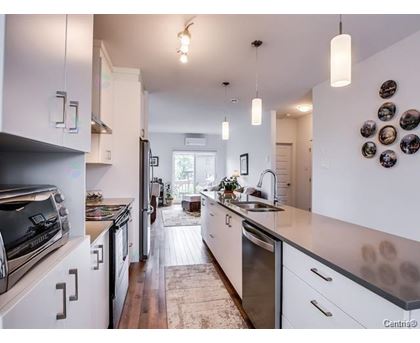 A kitchen with white cabinets and a wooden floor.