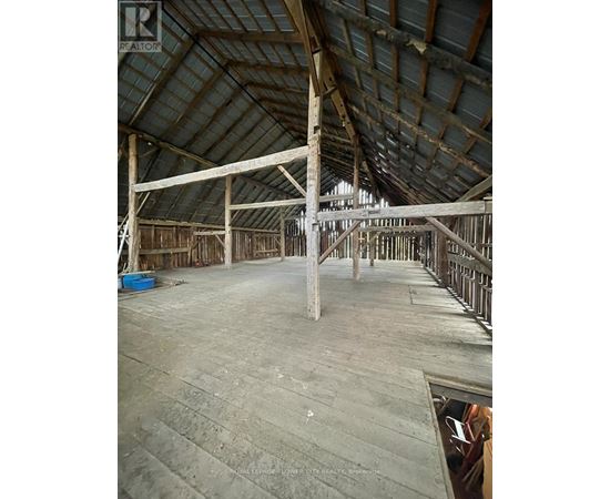 A large, empty attic space with wooden beams and a concrete floor.