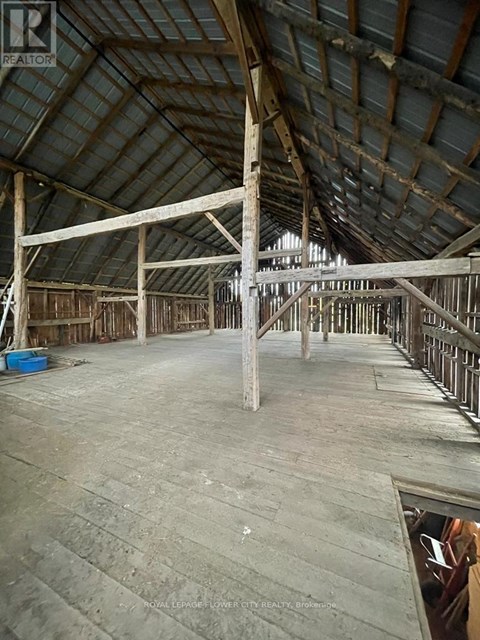 A large, empty attic space with wooden beams and a concrete floor.