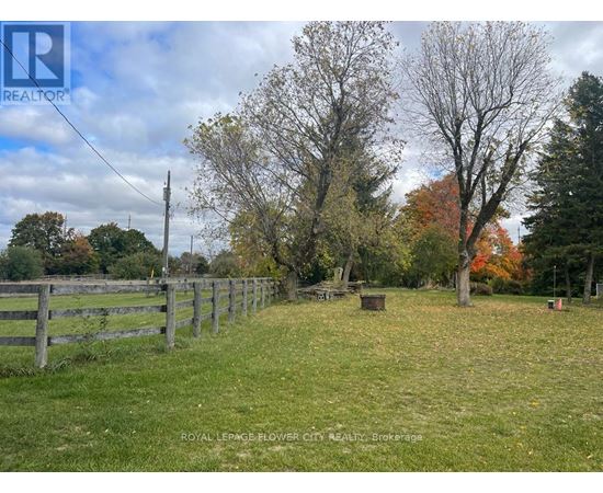 A fenced field with trees and a sign that says REALTOR.