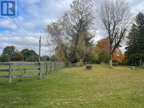 A fenced field with trees and a sign that says REALTOR.