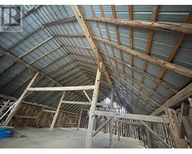 A large unfinished building with wooden beams and a glass roof.