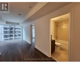 A spacious room with a wooden floor and a bathroom visible through the door.