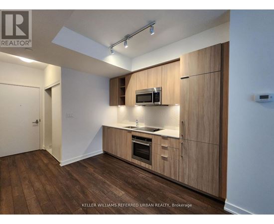 A kitchen with wooden cabinets and a microwave oven.