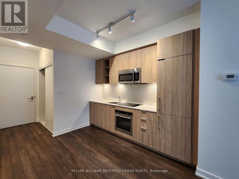 A kitchen with wooden cabinets and a microwave oven.