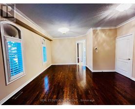 A spacious room with wood flooring and a window with blinds.