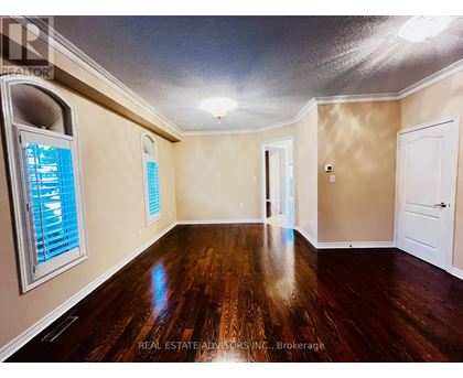 A spacious room with wood flooring and a window with blinds.