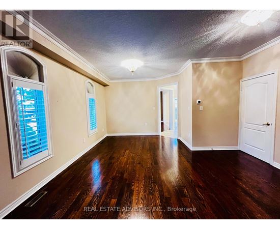 A spacious room with wood flooring and a window with blinds.