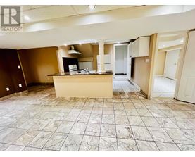 A large, empty room with a marble floor and a kitchenette in the middle.