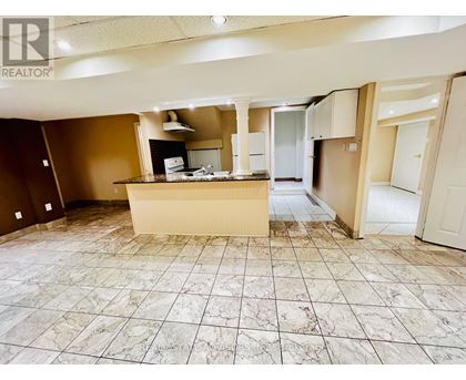 A large, empty room with a marble floor and a kitchenette in the middle.