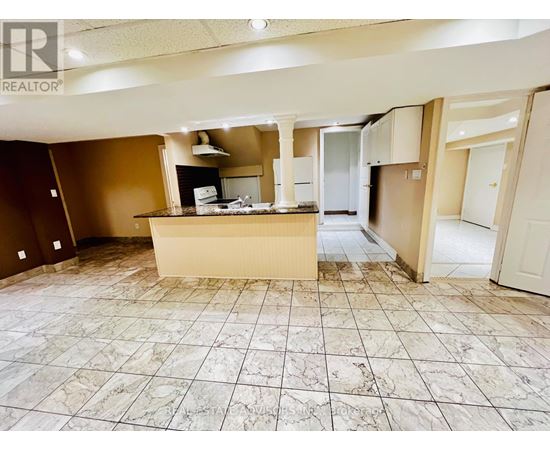A large, empty room with a marble floor and a kitchenette in the middle.