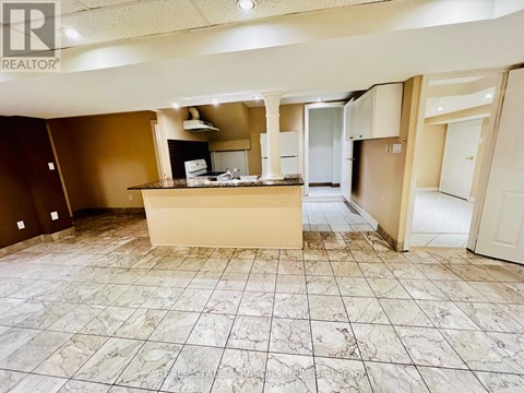 A large, empty room with a marble floor and a kitchenette in the middle.