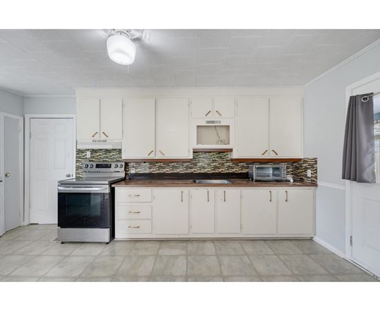 A kitchen with white cabinets and a stone backsplash.