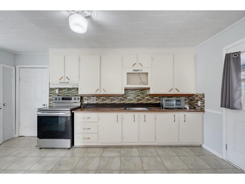 A kitchen with white cabinets and a stone backsplash.