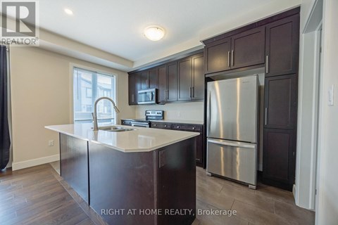 A kitchen with dark brown cabinets and a stainless steel refrigerator.