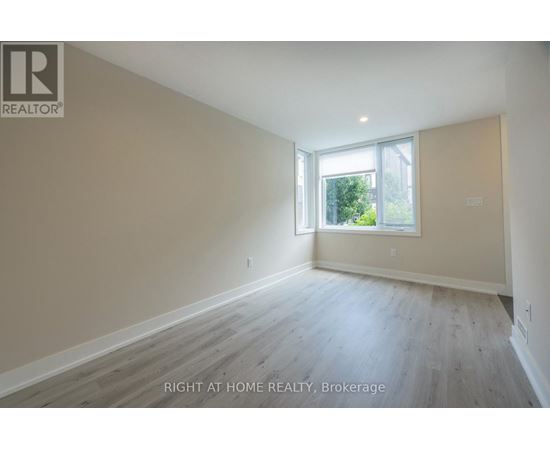 A spacious room with wooden flooring and a window letting in natural light.
