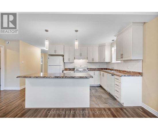 A kitchen with white cabinets and a marble countertop.