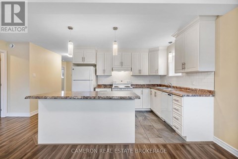 A kitchen with white cabinets and a marble countertop.