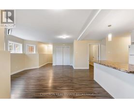 A spacious room with wooden flooring and white walls.