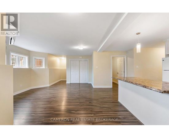 A spacious room with wooden flooring and white walls.