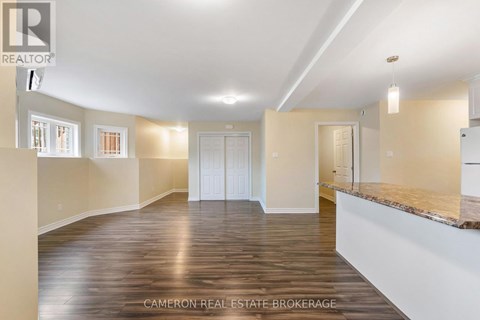 A spacious room with wooden flooring and white walls.