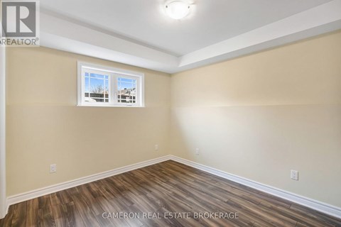 A room with wooden flooring and a window showing a building outside.