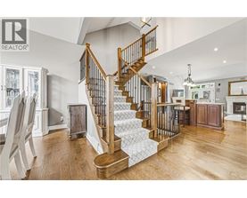 A wooden staircase with a metal railing leads to the upper floor of a spacious home.