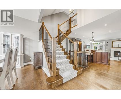 A wooden staircase with a metal railing leads to the upper floor of a spacious home.