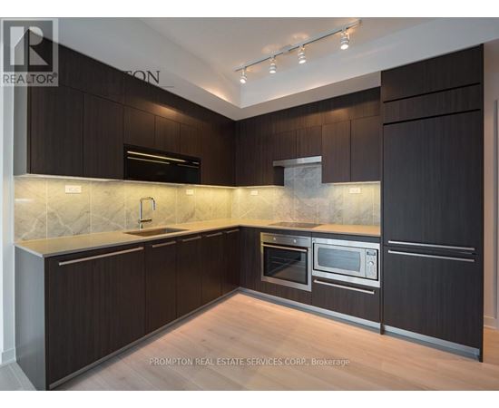 A kitchen with dark wood cabinets and a marble backsplash.