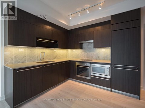 A kitchen with dark wood cabinets and a marble backsplash.