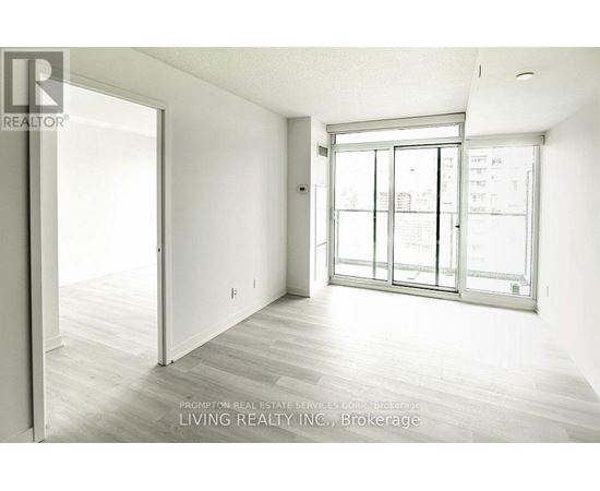 A spacious room with a sliding glass door leading to a balcony.