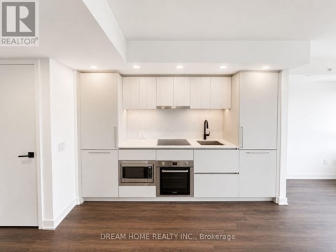 A modern kitchen with white cabinets and stainless steel appliances.
