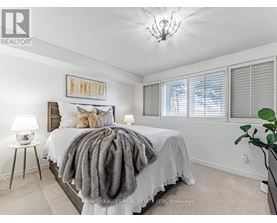 A bedroom with a bed covered in a grey blanket and a chandelier hanging from the ceiling.