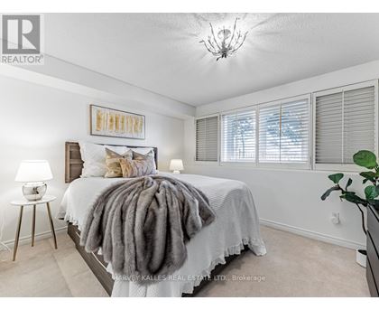 A bedroom with a bed covered in a grey blanket and a chandelier hanging from the ceiling.