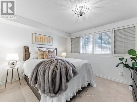 A bedroom with a bed covered in a grey blanket and a chandelier hanging from the ceiling.