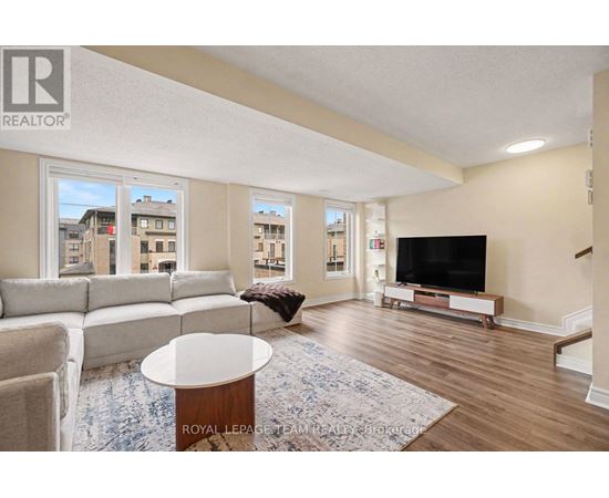 A living room with a white couch, a coffee table, and a television.