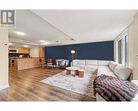 A spacious living room with a kitchen area in the background.