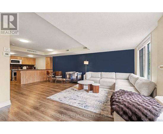 A spacious living room with a kitchen area in the background.